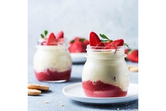Image Jars of pudding with sliced strawberries on top.